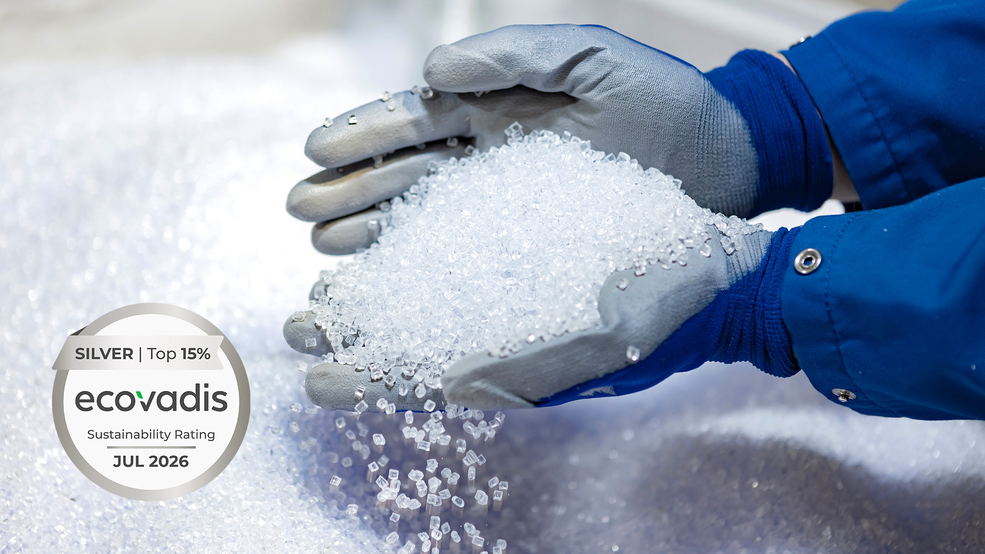 Hand holding recyclable raw material for plastic packaging. The EcoVadis Silver Medal, are visible in the image.