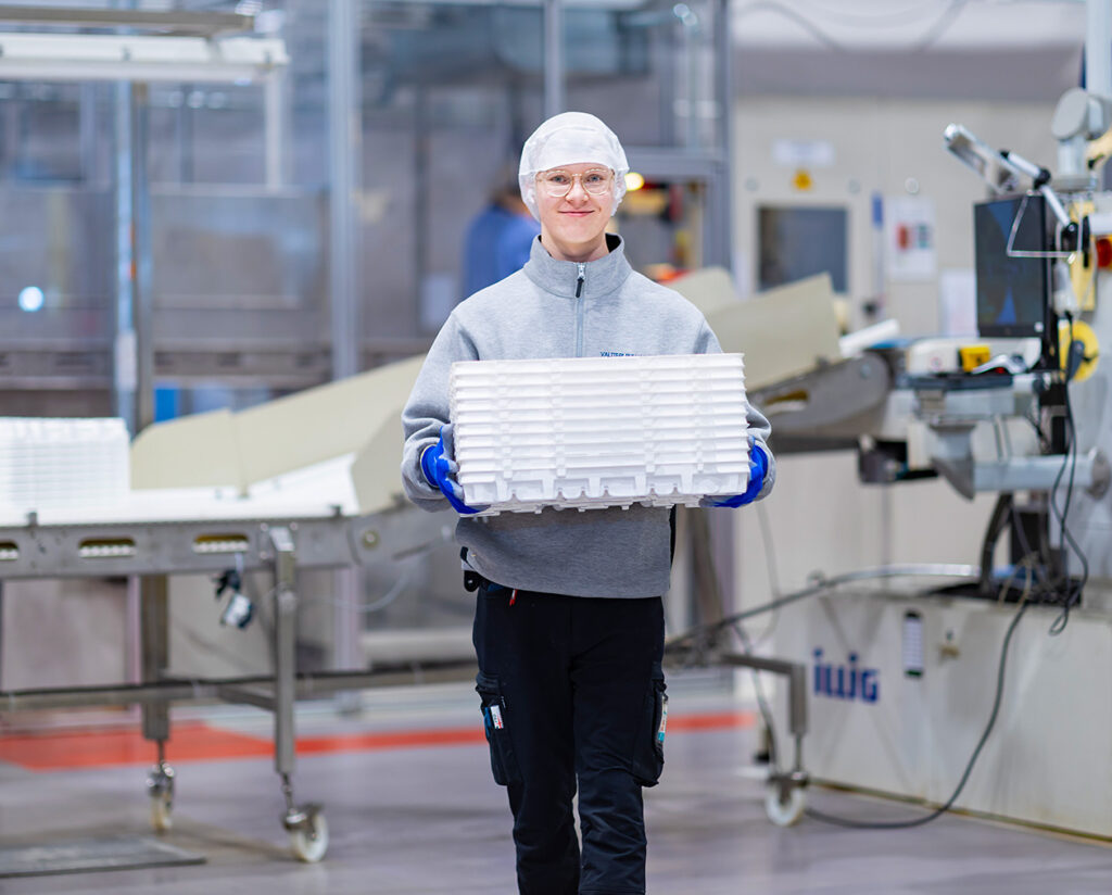 Production worker moving pharmaceutical packaging solutions in the production area with a smile.