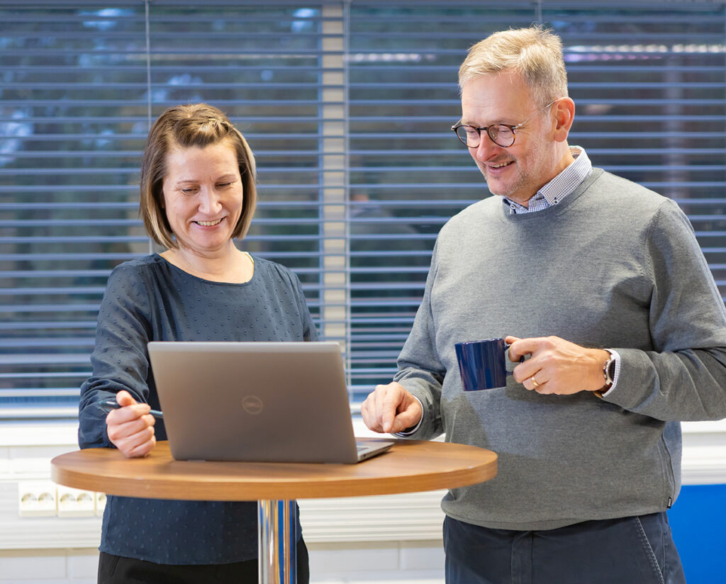 Two employees collaborating in a good mood at the office, looking at a laptop