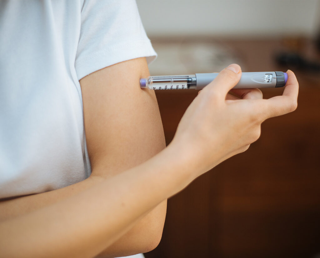 A person administering insulin, highlighting the importance of Satatuote's reliable packaging solutions for essential medicines