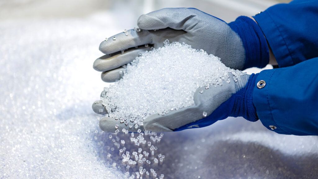 Hand holding recyclable raw material for plastic packaging.